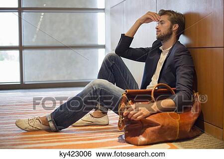 Man leaning against a wall at an airport View Large Photo Image Stock Photograph - Man leaning against a wall at an airport. Fotosearch