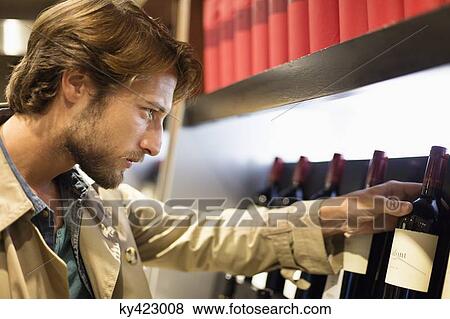 Man looking at a wine bottle View Large Photo Image Stock Photo - Man looking at a wine bottle. Fotosearch