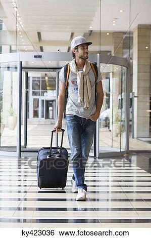 Stock Photograph - Man pulling his luggage at an airport. Fotosearch