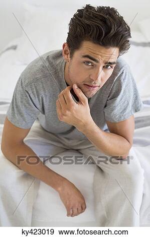 Stock Photo - Man sitting on the bed. Fotosearch