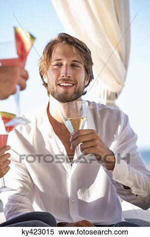 Stock Photography - Man sitting with friends enjoying drinks. Fotosearch