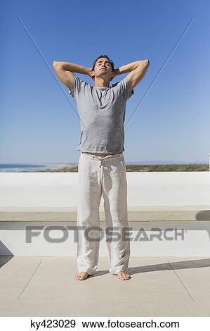 Man standing with hands behind head View Large Photo Image Stock Photo - Man standing with hands behind head. Fotosearch