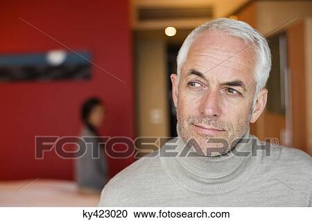 Man thinking in a hotel room with his wife in the background View Large Photo Image Stock Image - Man thinking in a hotel room with his wife in the background. Fotosearch