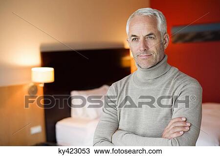 Man with arms crossed in a hotel room View Large Photo Image Stock Image - Man with arms crossed in a hotel room. Fotosearch