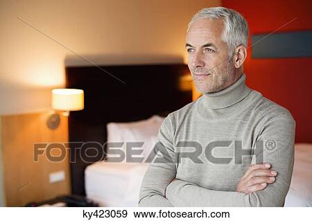 Stock Photo - Man with arms crossed in a hotel room. Fotosearch