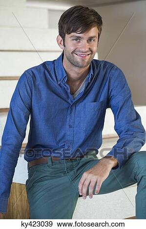 Portrait of a man smiling while sitting on staircase View Large Photo Image Stock Photo - Portrait of a man smiling while sitting on staircase. Fotosearch