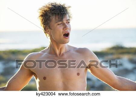 Shirtless man yawning with arm outstretched on the beach View Large Photo Image Picture - Shirtless man yawning with arm outstretched on the beach. Fotosearch