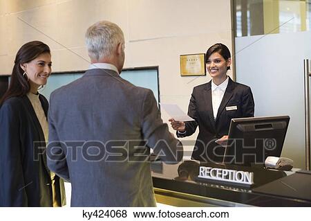 Business couple checking into hotel View Large Photo Image Stock Photo - Business couple checking into hotel. Fotosearch