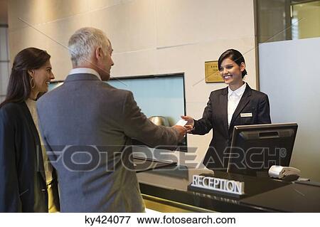 Stock Photo - Business couple getting key card at the hotel reception counter. Fotosearch