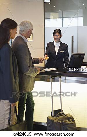 Stock Photo - Business couple paying with a credit card at the hotel reception counter. Fotosearch