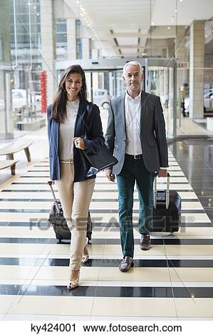 Business couple pulling suitcases in a hotel lobby View Large Photo Image Stock Image - Business couple pulling suitcases in a hotel lobby. Fotosearch