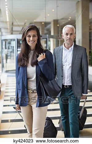 Business couple pulling suitcases in a hotel lobby View Large Photo Image Stock Image - Business couple pulling suitcases in a hotel lobby. Fotosearch