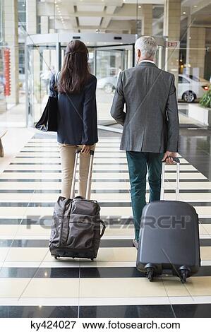Business couple pulling suitcases in a hotel lobby View Large Photo Image Stock Photo - Business couple pulling suitcases in a hotel lobby. Fotosearch