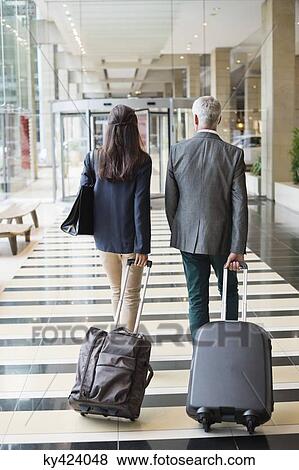 Business couple pulling suitcases in a hotel lobby View Large Photo Image Stock Photo - Business couple pulling suitcases in a hotel lobby. Fotosearch