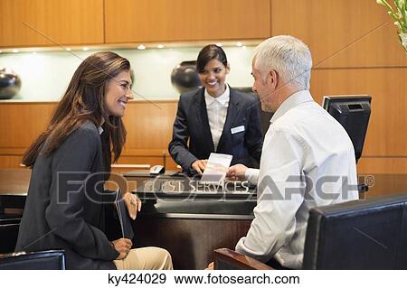 Business couple talking at a hotel reception counter View Large Photo Image Stock Photo - Business couple talking at a hotel reception counter. Fotosearch