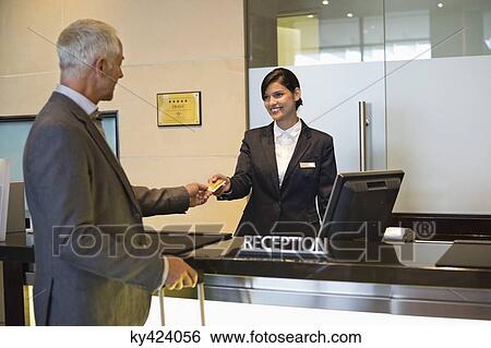 Stock Photograph - Businessman paying with a credit card at the hotel reception counter. Fotosearch