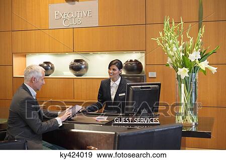 Businessman reading a brochure at a hotel reception counter View Large Photo Image Stock Photo - Businessman reading a brochure at a hotel reception counter. Fotosearch