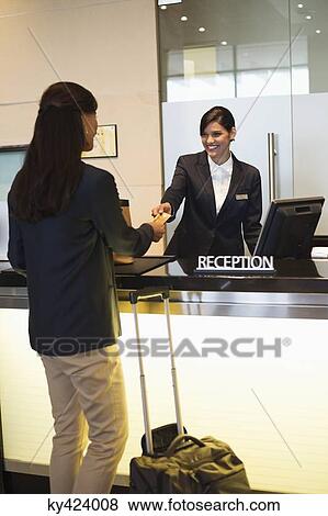 Businesswoman paying with a credit card at the hotel reception counter View Large Photo Image Stock Photo - Businesswoman paying with a credit card at the hotel reception counter. Fotosearch