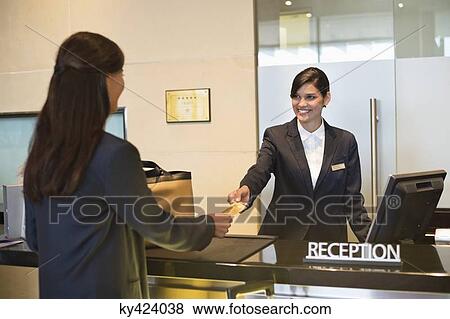 Businesswoman paying with a credit card at the hotel reception counter View Large Photo Image Stock Photo - Businesswoman paying with a credit card at the hotel reception counter. Fotosearch