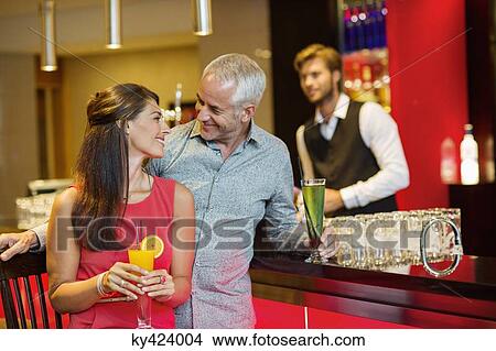 Picture - Couple enjoying drinks at the bar counter. Fotosearch