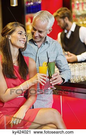 Couple enjoying drinks at the bar counter View Large Photo Image Stock Image - Couple enjoying drinks at the bar counter. Fotosearch