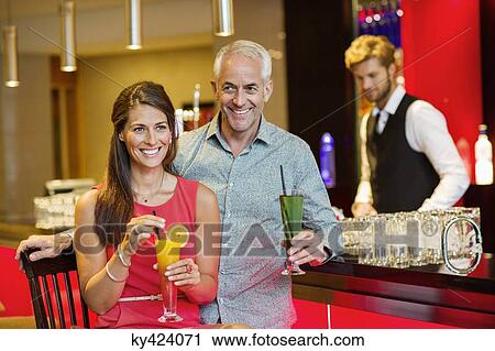 Couple enjoying drinks at the bar counter View Large Photo Image Stock Image - Couple enjoying drinks at the bar counter. Fotosearch