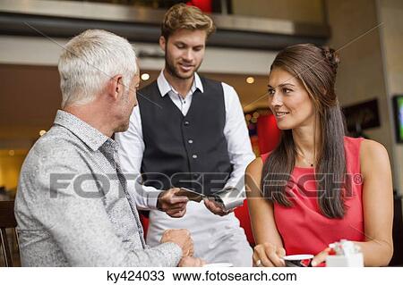 Couple paying with a credit card to a waiter in a restaurant View Large Photo Image Stock Image - Couple paying with a credit card to a waiter in a restaurant. Fotosearch