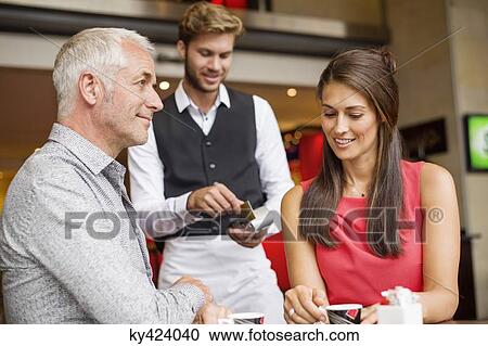 Couple paying with a credit card to a waiter in a restaurant View Large Photo Image Stock Image - Couple paying with a credit card to a waiter in a restaurant. Fotosearch