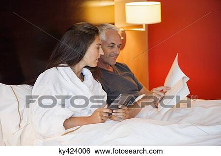 Couple reading a book in a hotel room View Large Photo Image Stock Photograph - Couple reading a book in a hotel room. Fotosearch