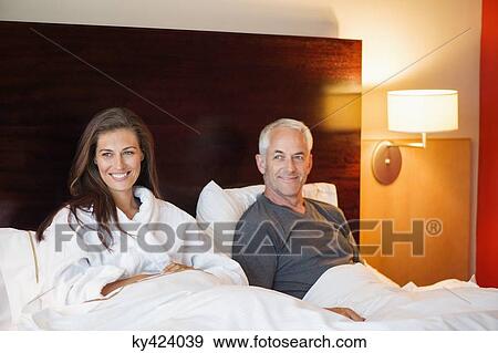 Couple sitting on the bed in a hotel room View Large Photo Image Stock Photo - Couple sitting on the bed in a hotel room. Fotosearch