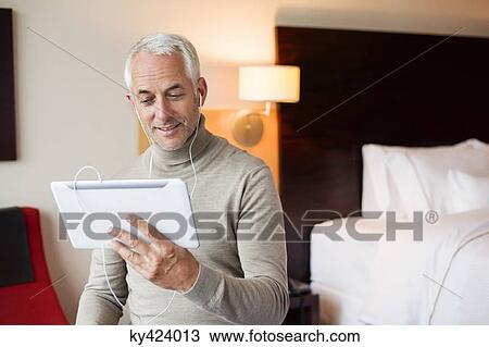 Man watching a movie on digital tablet in a hotel room View Large Photo Image Stock Image - Man watching a movie on digital tablet in a hotel room. Fotosearch