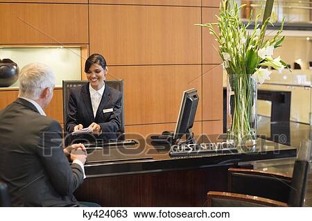 Receptionist giving brochures to a businessman at the hotel reception counter View Large Photo Image Stock Image - Receptionist giving brochures to a businessman at the hotel reception counter. Fotosearch
