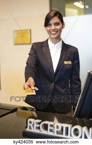 Receptionist holding a credit card and smiling at the hotel reception counter View Large Photo Image Stock Photography - Receptionist holding a credit card and smiling at the hotel reception counter. Fotosearch