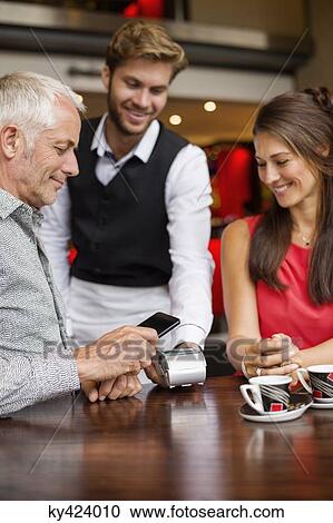 Waiter showing credit card reader to a couple on a table in a restaurant View Large Photo Image Stock Image - Waiter showing credit card reader to a couple on a table in a restaurant. Fotosearch