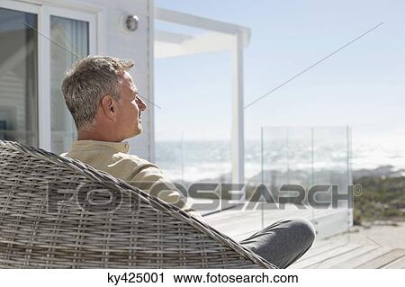 Man relaxing in a wicker chair View Large Photo Image Stock Image - Man relaxing in a wicker chair. Fotosearch