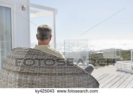 Stock Image - Man relaxing in a wicker chair. Fotosearch