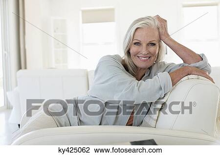 Portrait of a smiling woman sitting on a couch View Large Photo Image Stock Image - Portrait of a smiling woman sitting on a couch. Fotosearch