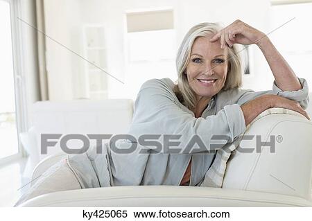 Portrait of a smiling woman sitting on a couch View Large Photo Image Stock Photography - Portrait of a smiling woman sitting on a couch. Fotosearch
