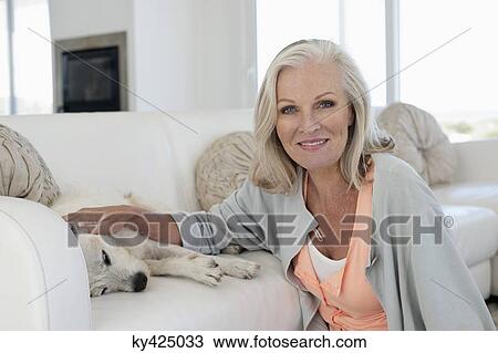 Portrait of a smiling woman stroking her dog lying on couch View Large Photo Image Stock Image - Portrait of a smiling woman stroking her dog lying on couch. Fotosearch