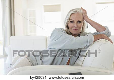 Portrait of a woman sitting on a couch View Large Photo Image Stock Image - Portrait of a woman sitting on a couch. Fotosearch