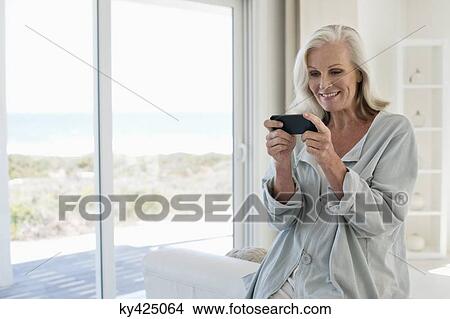 Smiling woman using a mobile phone View Large Photo Image Picture - Smiling woman using a mobile phone. Fotosearch