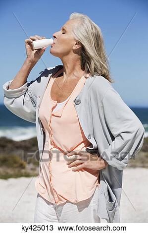 Stock Image - Woman enjoying probiotic drink on the beach. Fotosearch