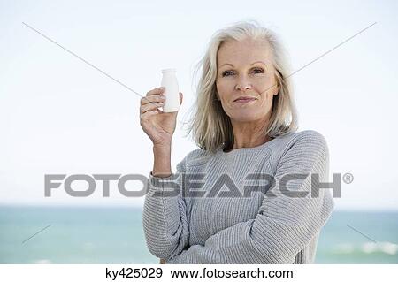 Woman holding a bottle of probiotic drink View Large Photo Image Stock Photo - Woman holding a bottle of probiotic drink. Fotosearch