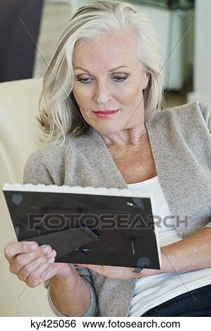 Stock Photograph - Woman looking at a picture frame. Fotosearch