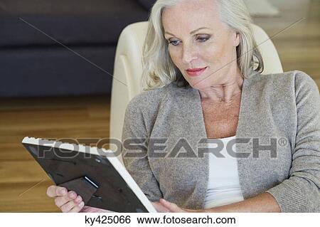 Stock Photograph - Woman looking at a picture frame. Fotosearch