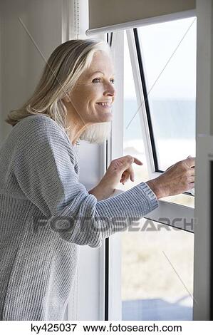 Woman looking through a window View Large Photo Image Stock Photo - Woman looking through a window. Fotosearch