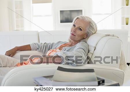 Woman sitting on a couch and thinking View Large Photo Image Stock Photo - Woman sitting on a couch and thinking. Fotosearch
