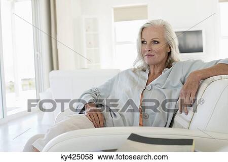 Woman sitting on a couch and thinking View Large Photo Image Stock Photo - Woman sitting on a couch and thinking. Fotosearch