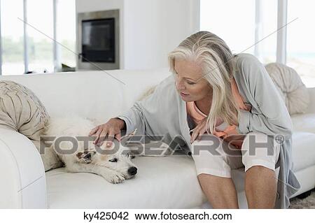 Stock Image - Woman sitting on a couch with her dog. Fotosearch