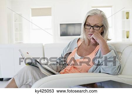 Woman sitting on a couch with holding a book and thinking View Large Photo Image Stock Image - Woman sitting on a couch with holding a book and thinking. Fotosearch